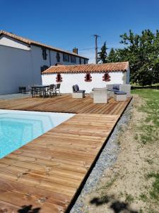 a wooden deck with a table and chairs next to a pool at La Longère de Mina in La Petite-Boissière