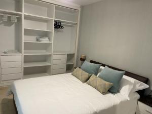 sypialnia z białym łóżkiem z poduszkami i półkami w obiekcie Apartamento Rio Mar w Marbelli +30 zdjęć