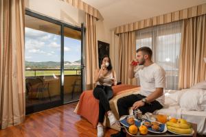 a man and a woman sitting on a bed eating food at Hotel Cristallo in Assisi