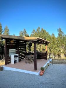 a wooden gazebo with a table and a grill at Monte da Rocha in Santiago do Cacém