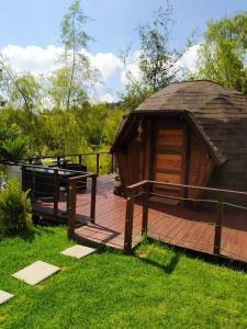 Una terraza de madera con un cenador en el césped. en Glamping Cantabria, en Tunja