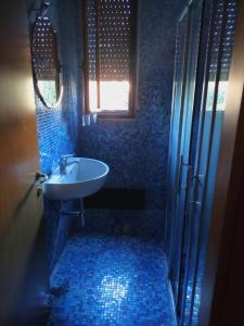 un bagno piastrellato blu con lavandino e finestra di Casa Mirella a Siena