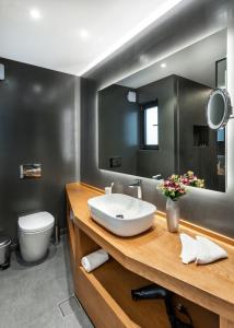 a bathroom with a sink and a toilet and a mirror at DAYS City Suites in Patra