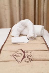 una pila de toallas en una cama con una servilleta en Cuzzy Inn Hotel, en Lahore