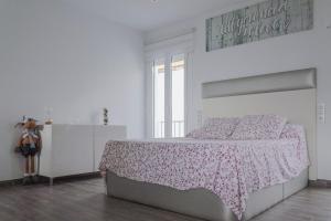 a white bedroom with a bed with a floral blanket at Loft of Love in Frigiliana