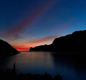 a sunset over a lake with a boat in the water at VistaLago Torbole in Nago-Torbole