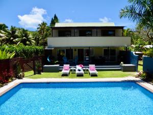 a house with a swimming pool in front of a house at Taakoka Muri Beach Villa in Rarotonga