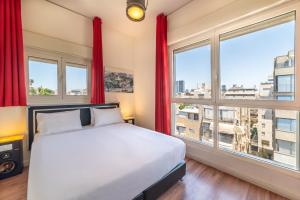 um quarto com uma cama e janelas com cortinas vermelhas em Ben Yehuda Apartments em Tel Aviv