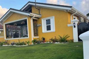 a yellow house with a fence in a yard at Villa Kalaya in Mammee Bay
