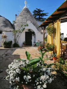 un giardino fiorito e una casa con tetto di paglia di Trulli la casa di Rosa ad Alberobello