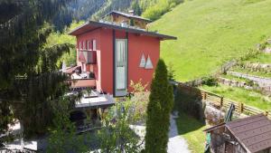 czerwony dom na wzgórzu obok płotu w obiekcie Haus Bodner-Scherer w mieście Mühlbach am Hochkönig