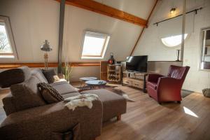 ein Wohnzimmer mit einem Sofa und einem TV in der Unterkunft Vakantiehuis De Drie Bruggen in Valkenswaard