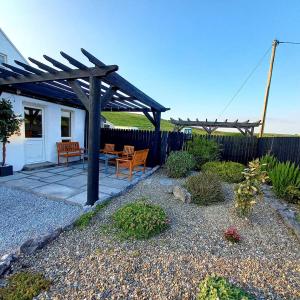 a patio with two benches and a wooden pergola at Cliffs View Self Catering @ Limestone Lodge in Doolin
