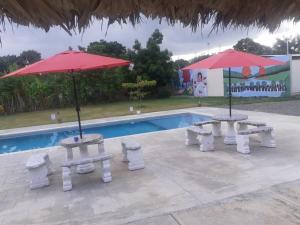 twee tafels en twee parasols naast een zwembad bij Hotel Anedi in Concepción de La Vega