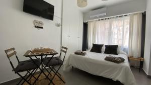 1 dormitorio con cama, mesa y TV en PLAYA, SOL Y CENTRO HISTORICO, en Málaga