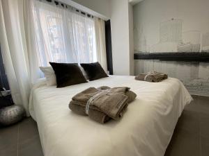 um quarto com uma cama branca e toalhas em PLAYA, SOL Y CENTRO HISTORICO em Málaga