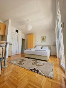 1 dormitorio con cama y alfombra en el suelo de madera en Apartments Bellevue - Otasevic, en Herceg-Novi