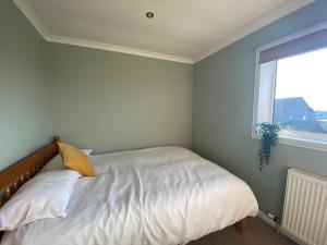 a bedroom with a bed with a yellow pillow and a window at Sigurd House in Thurso