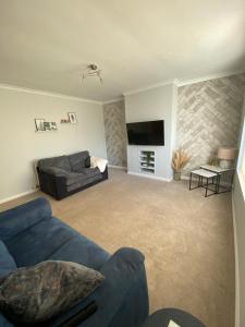 a living room with a blue couch and a tv at Sigurd House in Thurso