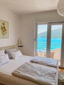 a bedroom with a bed with a view of the ocean at Apartments Bellevue - Otasevic in Herceg-Novi