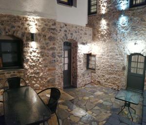 Habitación con pared de piedra con sillas y mesa. en RiverBed Traditional Guest House, en Litóchoron