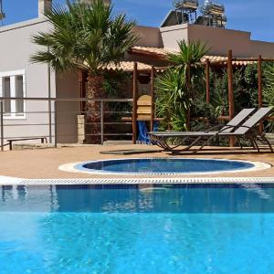 a swimming pool in front of a house at Alexena Apartments in Agia Galini