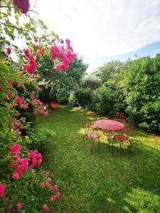 une table et des chaises roses dans une cour ornée de roses dans l'établissement Dépendance Cosy dans Maison Bordelaise à 200m du tram et du CHU, à Bordeaux