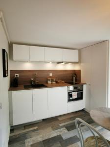 - une cuisine avec des placards blancs et un évier dans l'établissement Dépendance Cosy dans Maison Bordelaise à 200m du tram et du CHU, à Bordeaux