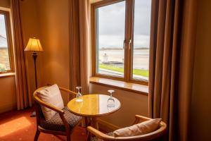 een kamer met een tafel, 2 stoelen en een raam bij Waterfront House & Restaurant in Enniscrone