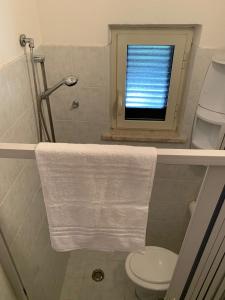 a bathroom with a toilet and a window with a towel at Quirino Residence in Gaeta