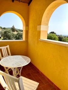 een tafel en stoelen op een balkon met 2 ramen bij La Vecchia Fornace in SantʼAnna Arresi