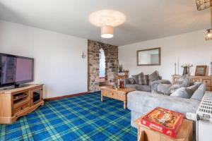 a living room with a couch and a tv at Meadowhead Cottage, Traditional Scottish Cottage in Waterside