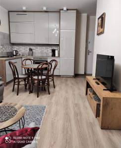 a living room with a kitchen and a table with chairs at VIEW 20 APARTAMENT in Giżycko