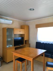 Habitación con mesa de madera con sillas y TV. en Parque de Campismo da Praia de Pedrogao, en Coimbrão