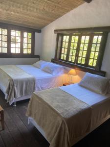 Dos camas en una habitación con dos ventanas. en Casa incrível na beira do rio Caraíva, en Caraíva