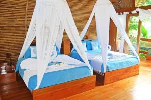 duas camas com cortinas brancas num quarto em Lagoona Beach Bungalows - Eco Stay em Pangandaran