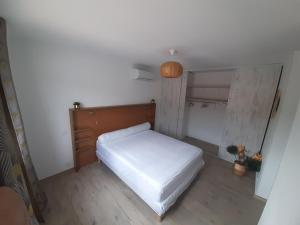 a small bedroom with a white bed and wooden floors at Villa_Culomba ALATA -T2 4 couchages in Alata