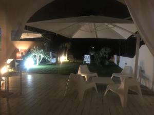 a patio with an umbrella and chairs at night at Villa a Diamante Sulla Spiaggia in Belvedere Marittimo