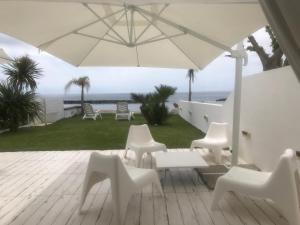a patio with white chairs and an umbrella at Villa a Diamante Sulla Spiaggia in Belvedere Marittimo