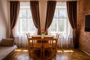comedor con mesa y sillas frente a las ventanas en Luxury apartment with Rynok square view, en Leópolis