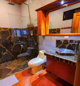 a bathroom with a toilet and a rock wall at Sunset Vista Lodge,Monteverde,Costa Rica. in Monteverde Costa Rica