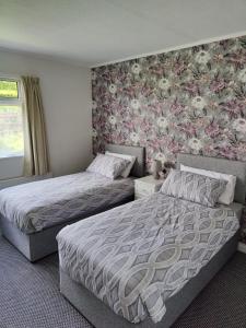 una camera con 2 letti e carta da parati floreale di The Bungalow Self-catering Accommodation a Ballybofey