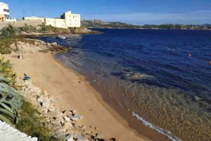 a beach next to the ocean with a building at Casa Maddalenina con giardino, vicino al mare! in La Maddalena +13 photos