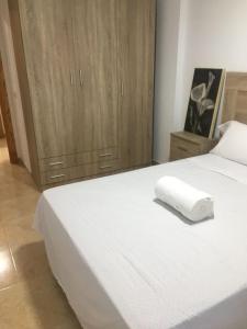 um quarto com uma grande cama branca e armários de madeira em 5 min de la playa em Roquetas de Mar