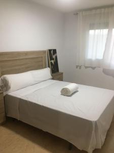 uma cama branca num quarto com uma janela em 5 min de la playa em Roquetas de Mar
