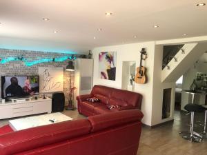 sala de estar con sofá rojo y guitarra en Chambon-sur-Lac en Chambon-sur-Lac