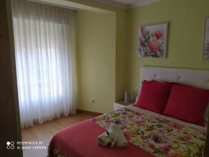 Un dormitorio con una cama con almohadas rojas y una ventana en Apartamento Manuel, en Vilagarcía de Arousa