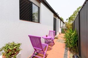 three purple chairs and a table on a patio at Arcade Inspiration Gold-Coast Stay in Gold Coast