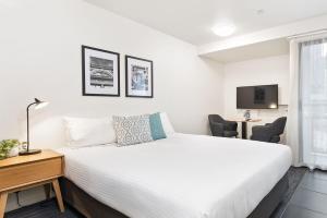 um quarto com uma cama, uma secretária e uma televisão em City Edge North Melbourne Apartment Hotel em Melbourne