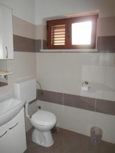 a bathroom with a white toilet and a window at Room in Susak with air conditioning, W-LAN (3865-4) in Susak